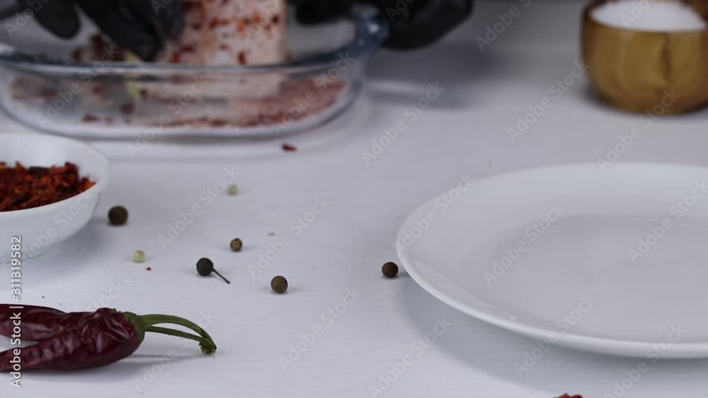 The chef soaks a large piece of pork fat with salt, paprika and red hot pepper and puts it on a white plate The chef soaks a large piece of pork fat with salt, paprika and red hot pepper and puts it on a white plate