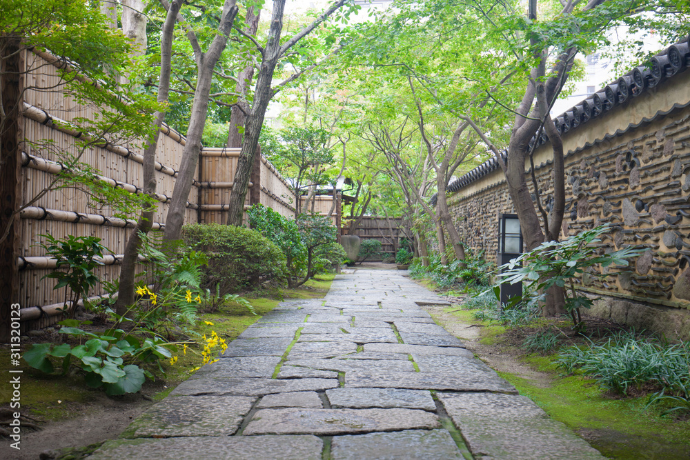 Path of plated stones among the Green trees in Japanese Garden. Meditative stone walkway. Garden architecture, pathway accessory to garden. the park at morning. Black rocks walking way in tropical.