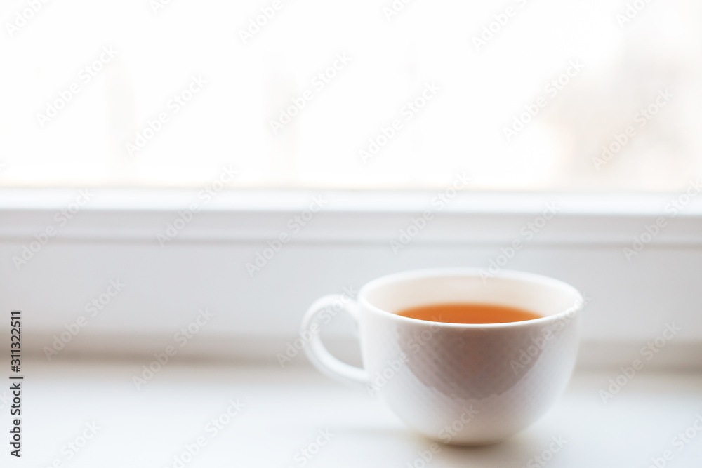 white cup with tea stands on the windowsill on the window white cup with tea stands on the windowsill on the window