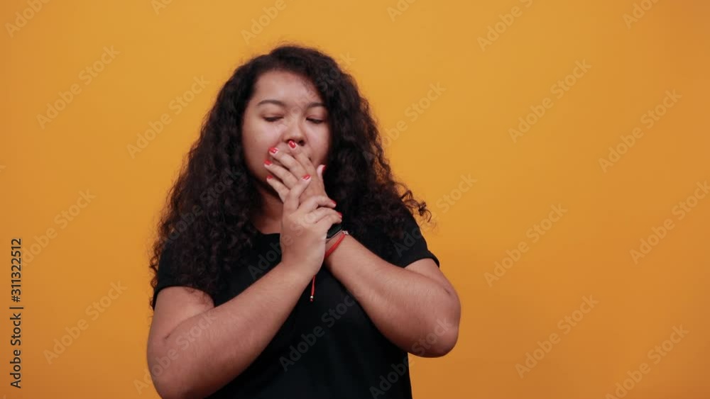 Shocked young woman with overweight covering mouth with hands, looking aside over isolated orange background wearing fashion black shirt. People lifestyle concept. Shocked young woman with overweight covering mouth with hands, looking aside over isolated orange background wearing fashion black shirt. People lifestyle concept.