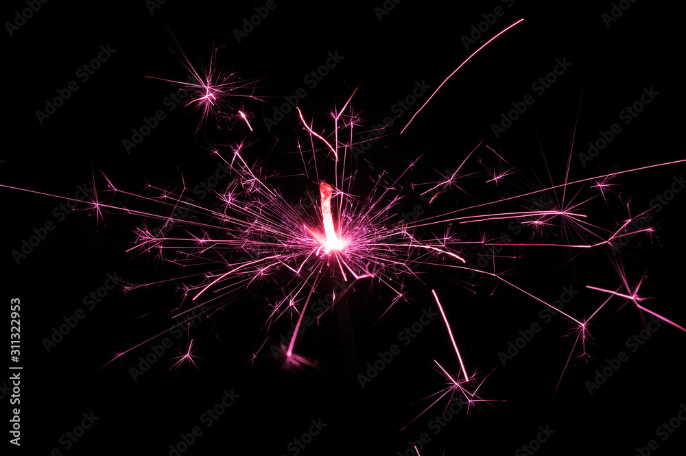 Sparkler in pink and white light on a black background. Sparkler in pink and white light on a black background.