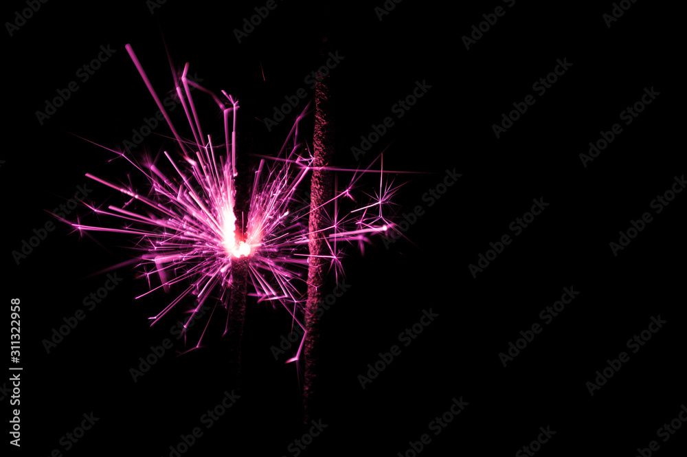 Sparkler in pink and white light on a black background. Sparkler in pink and white light on a black background.