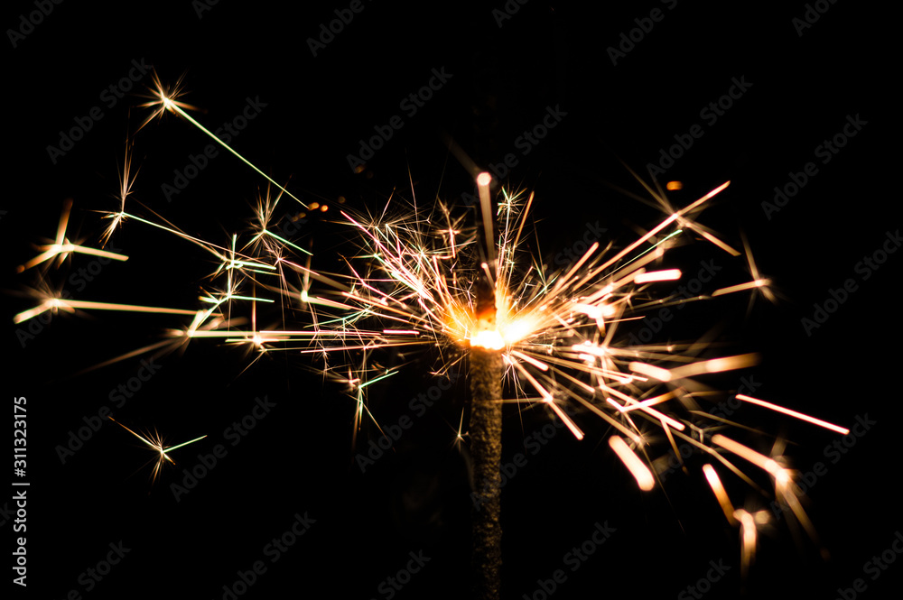 Sparkler in yellow and orange light on a black background.