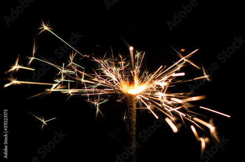 Sparkler in yellow and orange light on a black background.