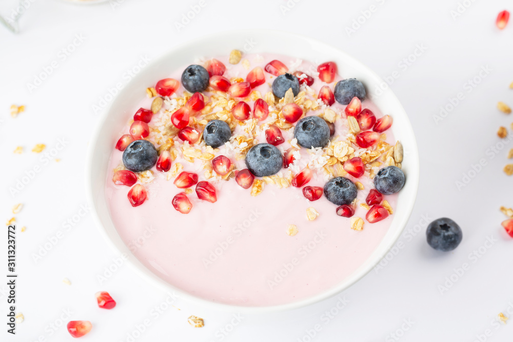 Fototapeta premium Smoothie bowl with yogurt, granola, blueberries, pomegranate seeds and shredded coconut. Healthy breakfast.