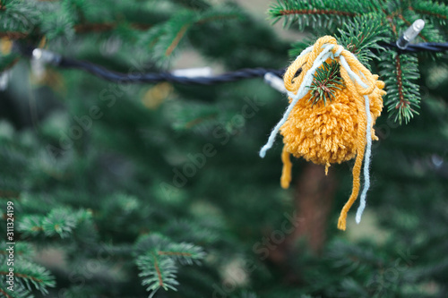 Wool handmade decoration on a Christmas tree outdoor. Diy yarn crafts creative ideas for children. Environment, recycle and zero waste concept. Selective focus, copy space.