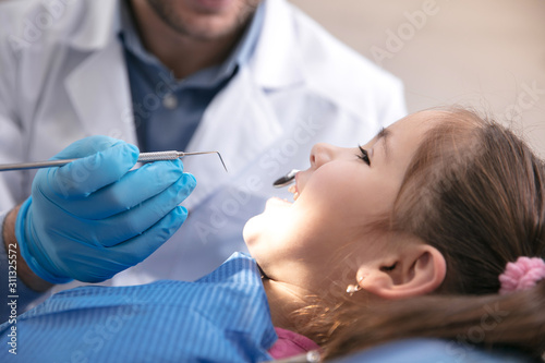 Young caucasian girl calm and happy visiting dentist s office for prevention and treatment of the oral cavity. Child and doctor while checkup teeth. Healthy lifestyle  healthcare and medicine concept.