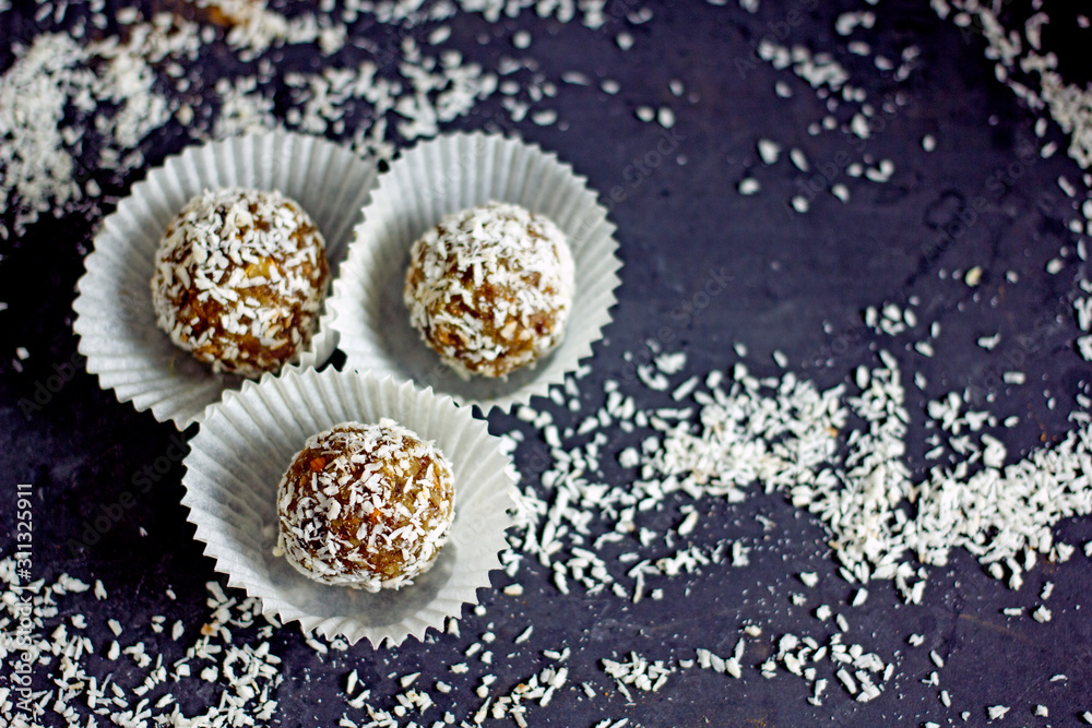 Raw food candy. Handmade vegan sweets made from almonds, walnuts, dates, raisins, coconut and cocoa. Raw food candies in coconut and cocoa close-up. Healthy vegan sweets concept. Raw food candy. Handmade vegan sweets made from almonds, walnuts, dates, raisins, coconut and cocoa. Raw food candies in coconut and cocoa close-up. Healthy vegan sweets concept.