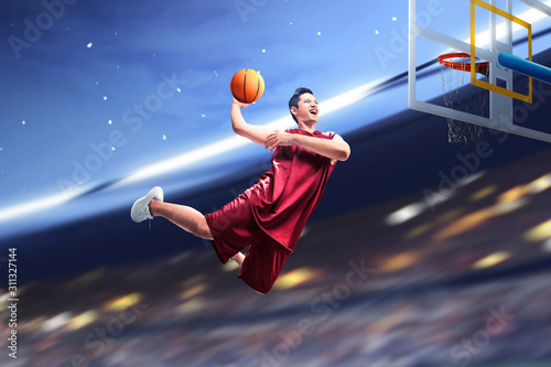 Asian basketball player man jumps in the air with the ball trying to score © Leo Lintang