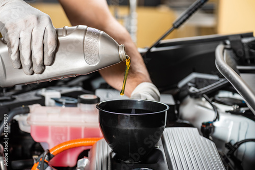 partial view of mechanic pouring motor oil at car engine