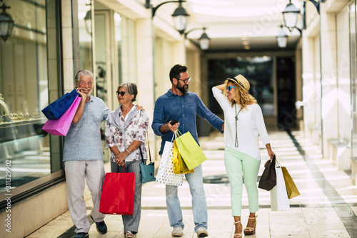 group of four people attended the mall going shopping together with shopping bags on their hands - seniors and adults at the stores
