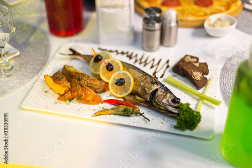 Plate of juicy fish served with french fries and lemon in a restaurant