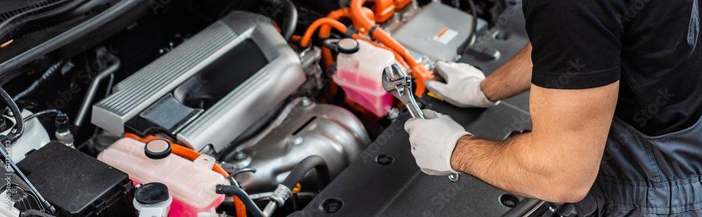 Fototapeta premium partial view of mechanic inspecting car engine compartment, panoramic shot