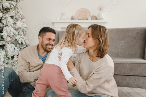 Family Christmas morning in a bright minimalistic living room near the Christmas tree.