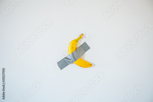 A banana taped to the white wall. photo