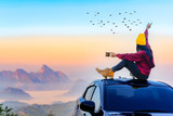Woman traveller enjoy coffee time on her owns roof of the car with scenery view of the mountain and mist morning in background