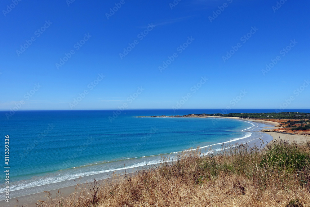 Summer view of pure blue crescent shaped beach coastline, Great Ocean Road, Victoria, Australia.
