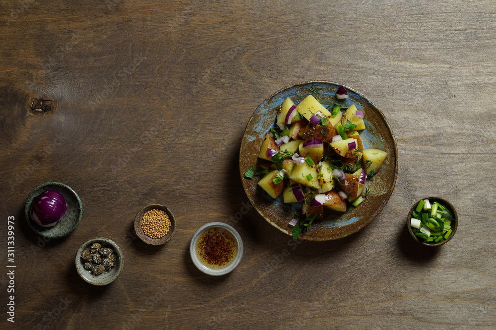 Salad of boiled potatoes with Dijon mustard, red onions and herbs. Saucers with ingredients: capers, olive oil with spices, red and green onions, mustard peas. Horizontal layout, top view, copy space. Salad of boiled potatoes with Dijon mustard, red onions and herbs. Saucers with ingredients: capers, olive oil with spices, red and green onions, mustard peas. Horizontal layout, top view, copy space.
