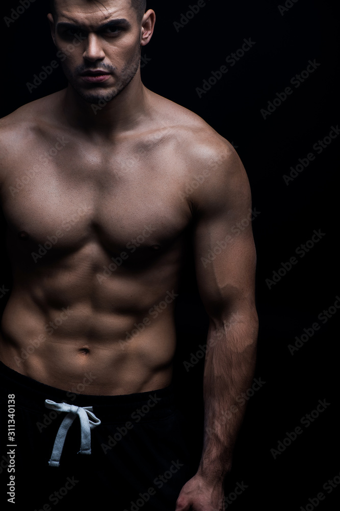 Fototapeta premium sexy muscular bodybuilder with bare torso isolated on black