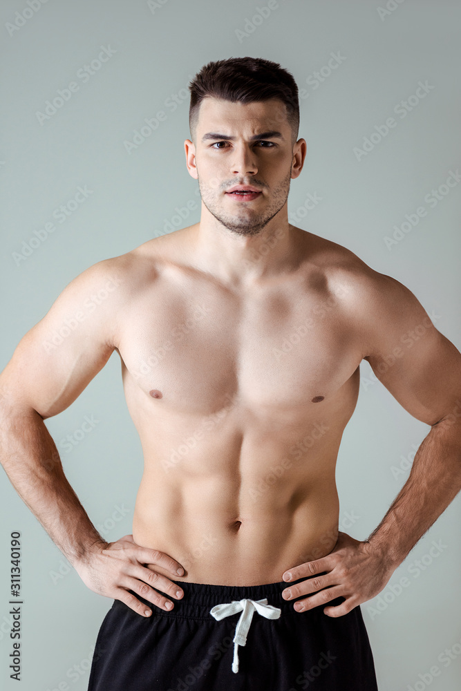 sexy muscular bodybuilder with bare torso posing with hands on hips isolated on grey sexy muscular bodybuilder with bare torso posing with hands on hips isolated on grey