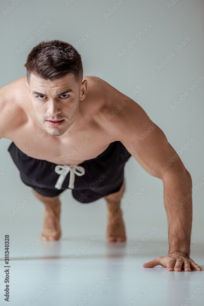 sexy muscular sportsman with bare torso doing push ups on grey sexy muscular sportsman with bare torso doing push ups on grey