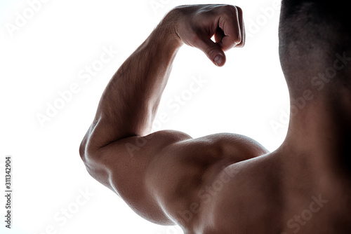 cropped view of muscular bodybuilder showing triceps in shadow isolated on white