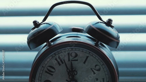 An old vintage alarm clock chimes at twelve o'clock.