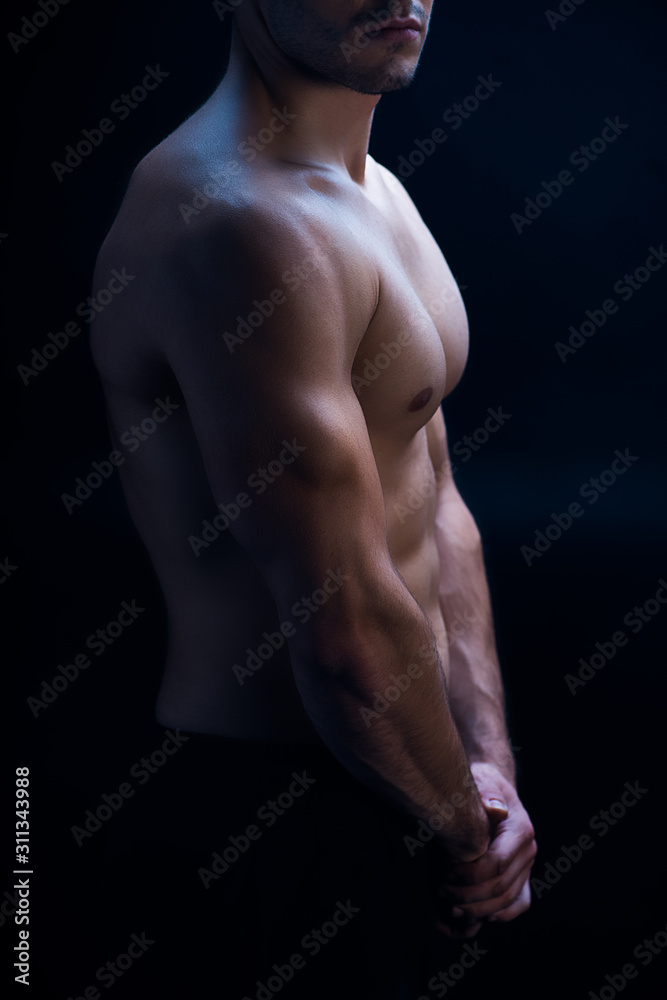side view of sexy muscular bodybuilder with bare torso posing isolated on black side view of sexy muscular bodybuilder with bare torso posing isolated on black