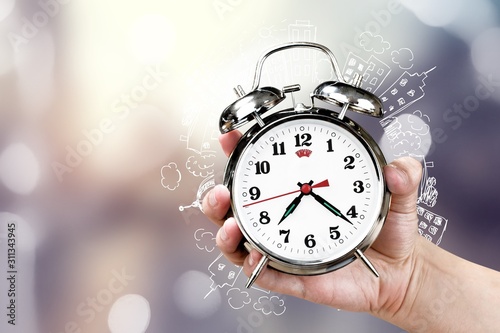Woman holding alarm clock in hand on bokeh background