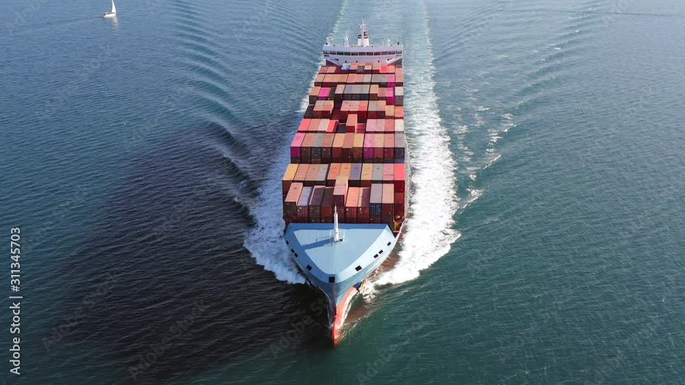 Large loaded Container Ship roaring across the open sea, Aerial view.