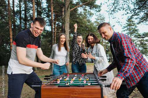 Friends play table football or kicker outdoors. Players and fans rejoice in the victory. photo