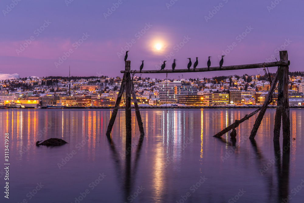 Amazing sunrise with amazing magenta color and moon over Tromso, Norway. Fisherman's building . Polar night. long shutter speed