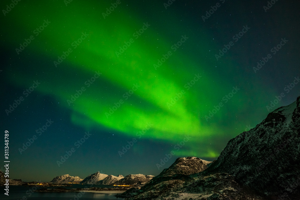 winter landscape with aurora, sea with sky reflection and snowy mountains. Nature, Lofoten islands, Norway.