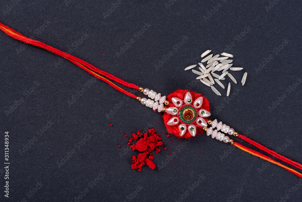Raksha Bandhan : Rakhi with rice grains and kumkum on black background ...