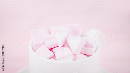 Cup of pink marshmallow hearts on a pale pink background. Valentines day love concept. Copy space, 16:9 panoramic format