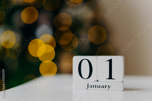 Winter time, first of January. Calendar with numbers and month on white desk against shing lights and New Year background. First month of year photo