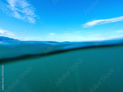 Seascape. Cloudy blue sky over the blue surface of the sea on a sunny day.