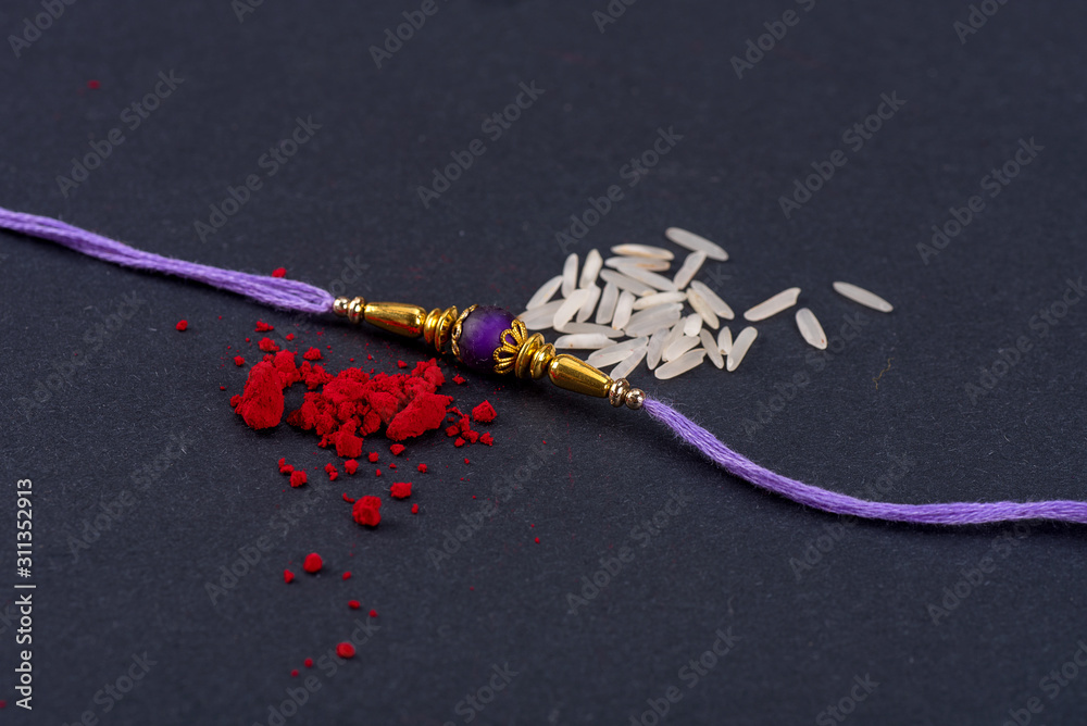 Raksha Bandhan : Rakhi with rice grains and kumkum on black background ...