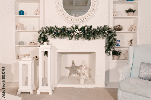 Christmas tree and a chair stands near the fireplace  and other holiday decorations in white loft