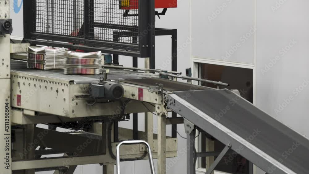 Binded pile of newspaper at the conveyor belt of a printing factory Binded pile of newspaper at the conveyor belt of a printing factory