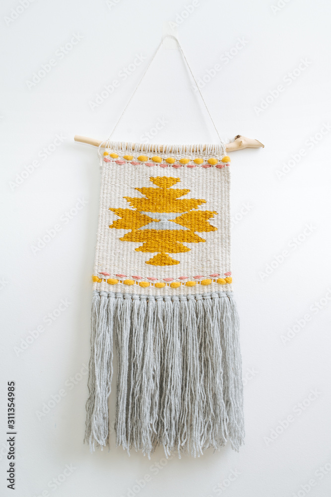 Fototapeta Macrame tapestry with yellow-colored patten hanging on the wall