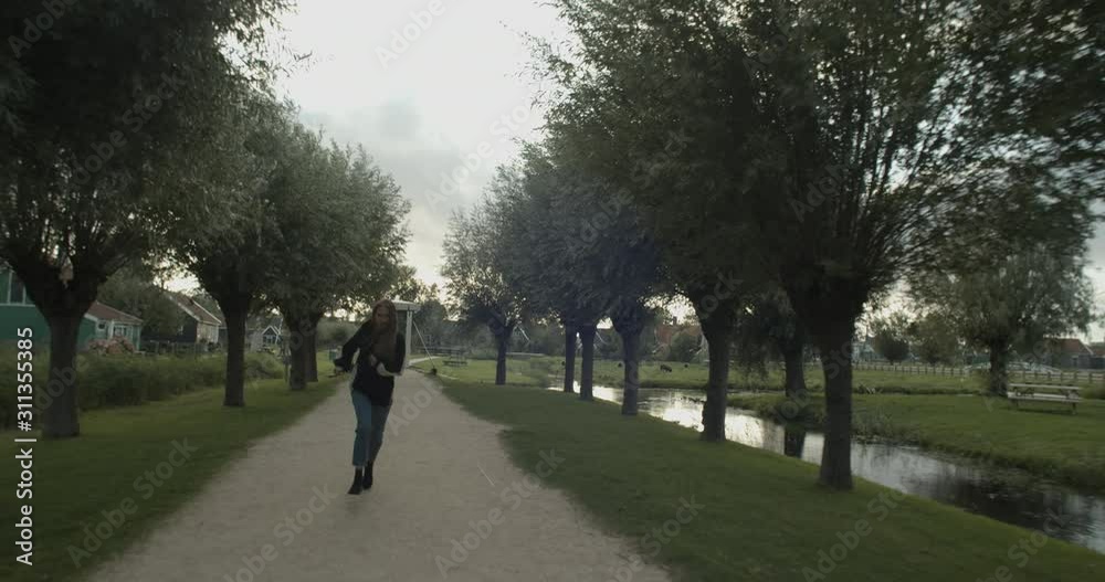 Young blonde woman wearing black hoodie posing while running outside in the old European Dutch village Young blonde woman wearing black hoodie posing while running outside in the old European Dutch village