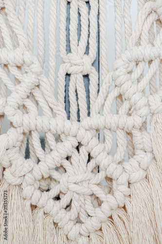 Macrame tapestry up close. Knots, ropes and tassels arranged in a pattern.