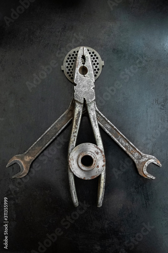 Repair tools form a symbolic composition. Pliers creative. Metal creative. Steel tools decor. Hands outstretched. A fake saint, a halo is a detail from a meat grinder.