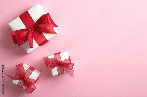 White gift boxes with red ribbon bow on pastel pink background. Saint Valentine's Day surprise, love concept. Flat lay, top view.