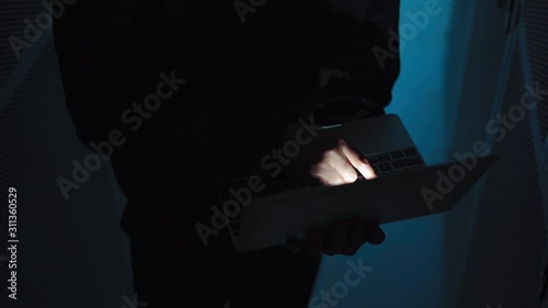 A computer programmer or hacker prints a code on a laptop keyboard to break into a secret organization system.