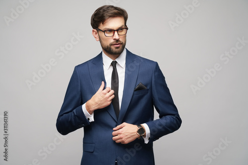 Portrait of a handsome young stylish businessman wearing glasses over grey background