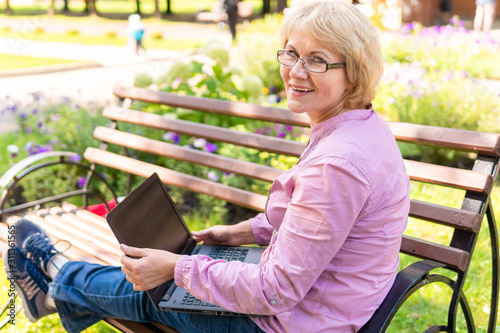 A woman with a laptop looks at a document in outdoors