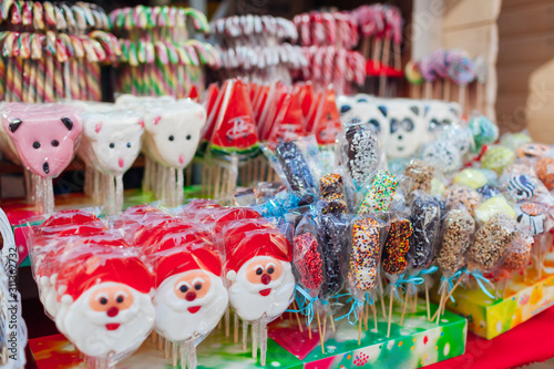 Christmas and New year's street fair sweet food. Santa shaped candies, lollypops and candy canes sold in outdoor shop