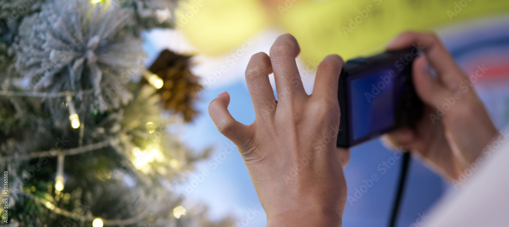 close up and soft focus hand of asian woman A woman with a camera to take photos of christmas decorative tree